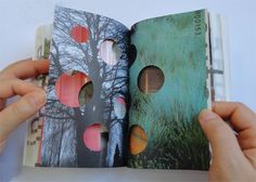 two hands are holding an open book with pictures on the pages and trees in the background