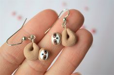 a person is holding two small rocks in their hand and earrings are made out of clay