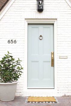 a white house with a blue front door and potted plants on the side walk