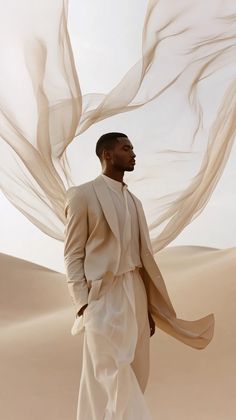 a man standing in the desert wearing a white suit and shawl over his head