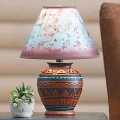 a lamp sitting on top of a wooden table next to a potted succulent