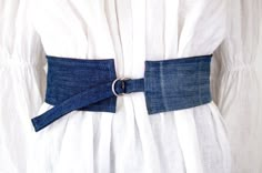 a woman wearing a white dress with a blue belt on it's lapel