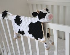 a crocheted black and white cow hanging from the side of a crib