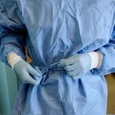 a person in scrubs and gloves is holding something with both hands on their hip