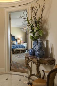 a room with a table and vases on the floor next to a door that leads to a bedroom