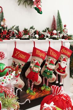 christmas stockings with personalized names and santa hats hanging from the fireplace mantels