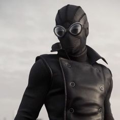 a man in a black leather jacket and goggles with his hands on his hips