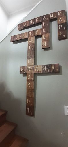 a cross made out of scrabble tiles on the wall next to some stairs