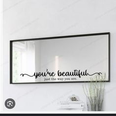 a mirror with the words you're beautiful on it and a plant next to it