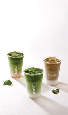 three cups filled with different types of green drinks on top of a white countertop