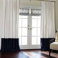 a living room with white and blue drapes on the windowsill, dark wood flooring