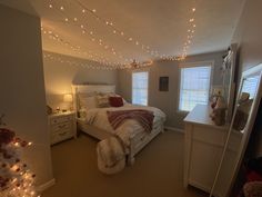 a bed room with a neatly made bed and christmas lights hanging from the ceiling above it