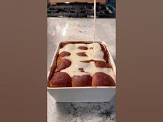 a pan filled with cake covered in icing and sitting on top of a counter