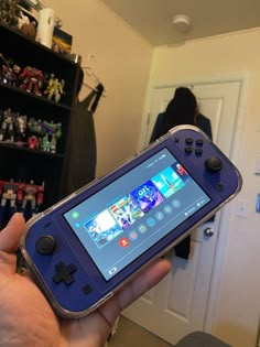 a person holding up a game controller in their hand with the screen turned on and showing