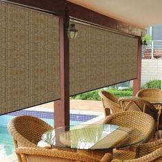 an outdoor dining area with wicker furniture and blinds on the side of the pool