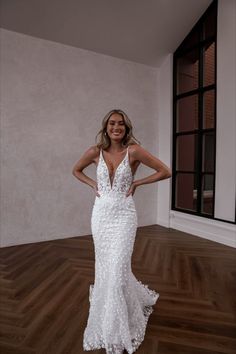 a woman in a white dress standing on a wooden floor with her hands on her hips