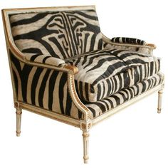 a zebra print chair with gold trimmings on the legs and arms, sitting in front of a white background