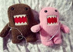 two stuffed animals that are laying on a bed with wires attached to the headphones