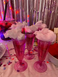 three pink vases filled with cotton balls on top of a table next to confetti