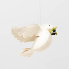 a white bird hanging from a string with a flower in it's beak and wings