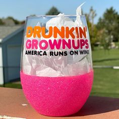 a wine glass that has been decorated with pink and orange glitter in front of a house