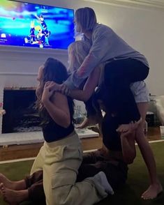 three people sitting on the floor in front of a television with their arms around each other