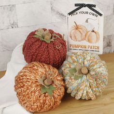 three knitted pumpkins sitting on top of a wooden table