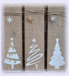 three wooden signs with christmas trees painted on them, tied together and decorated with gold stars