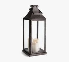 a black lantern with two white candles inside