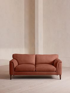 an orange couch sitting on top of a hard wood floor next to a white wall