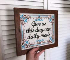 someone is holding up a cross - stitch sign that says give us this day our daily med