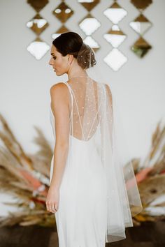 the back of a bride's dress in front of a wall with decorative art on it