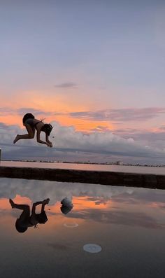 a person jumping into the water with their feet in the air while another person watches