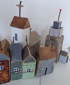 several small wooden houses are stacked on top of each other in front of a white wall