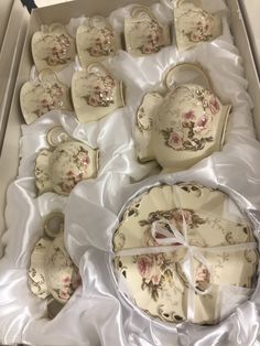 a box filled with lots of pretty china plates and cups on top of a white table cloth