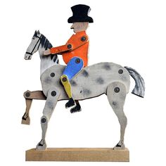 a wooden toy horse with a man on it's back sitting on a stand