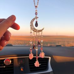 a car dashboard with a person holding up a necklace