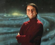 a man in a red shirt smiles at the camera while standing in front of a space background