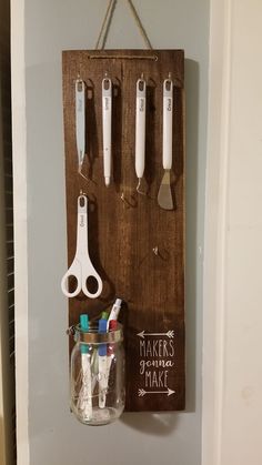 a mason jar hanging on a wall with kitchen utensils and scissors attached to it