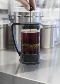 a person using a blender to make liquid in a cup on top of a counter