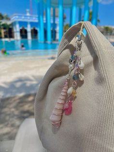 a close up of a person's hand holding a necklace with shells and beads