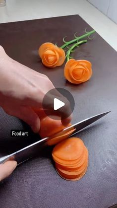 a person cutting carrots with a knife on top of a table next to flowers