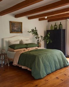 a bed sitting in a bedroom next to a window with wooden beams on top of it