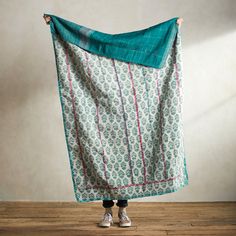 a woman holding up a green and white blanket