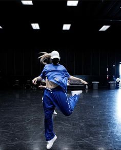 a woman is dancing in the middle of an empty room with black walls and flooring