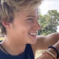 a young man smiling and wearing a bracelet