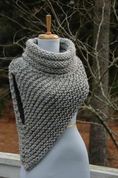 a gray knitted shawl on a mannequin with trees in the background