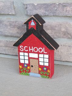 a small red school building with flowers painted on it