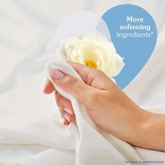 a woman's hand holding a white flower with the words more softening ingredients above it