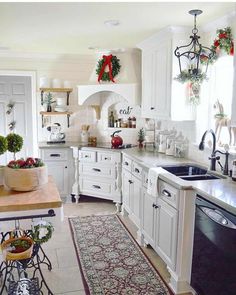 An arched range hood with wooden corbels is mounted over an arched kitchen niche. A grid tile backsplash merges with a white shiplap to cover the walls. Black hardware is installed on white cabinets. Farmhouse decor provides this kitchen with a country charm...   Image: simple_and_lovely